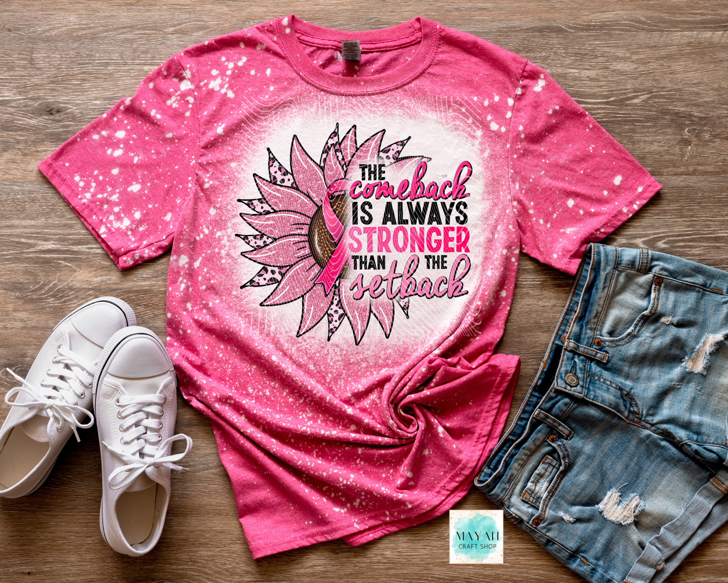 Pink t-shirt with sunflower design and motivational quote, paired with white sneakers and denim shorts on a wooden surface.