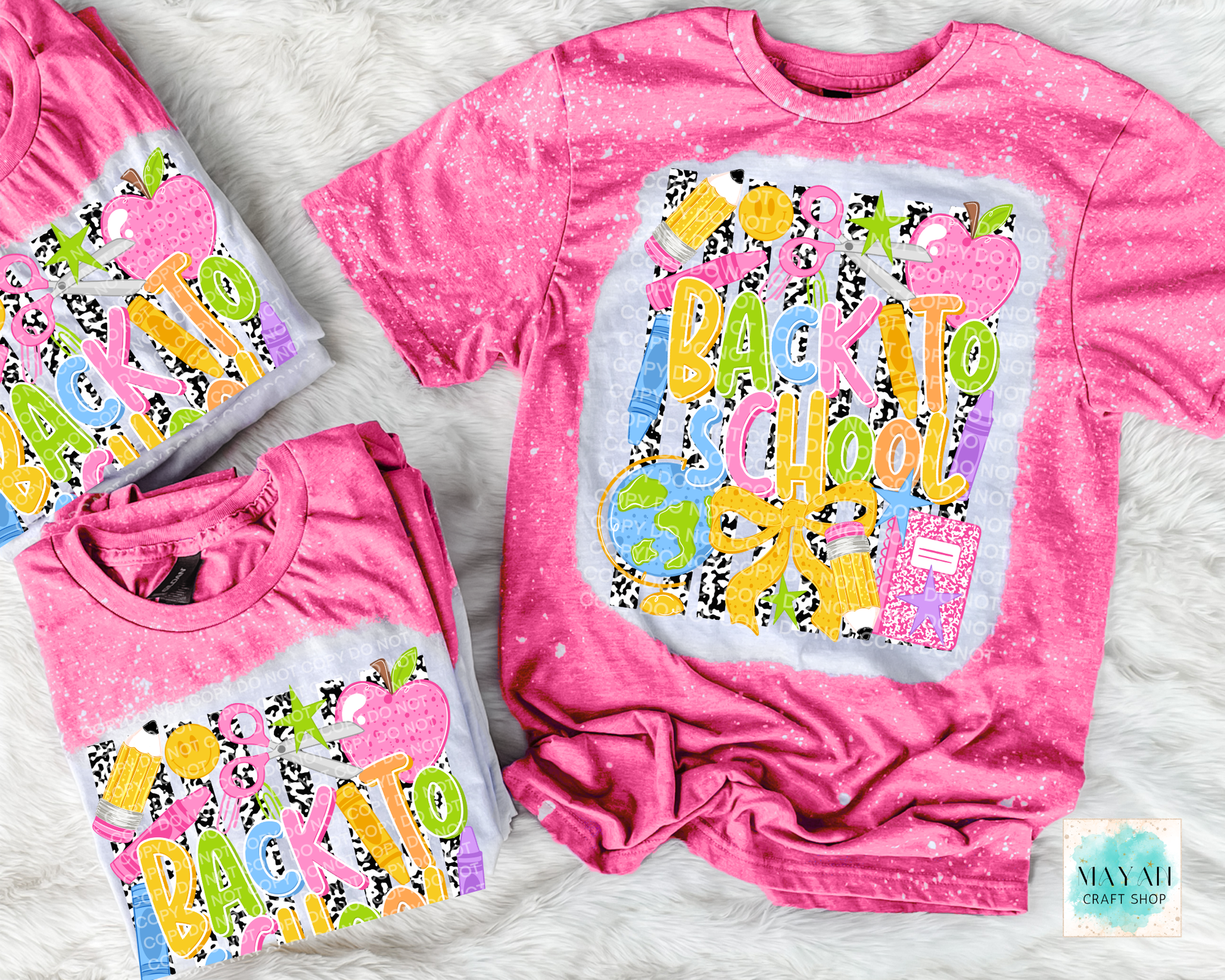 Three pink short-sleeve graphic T-shirts arranged on a white faux-fur surface. The shirts feature a colorful 'Back to School 3' design with apples, books, and patterned lettering.