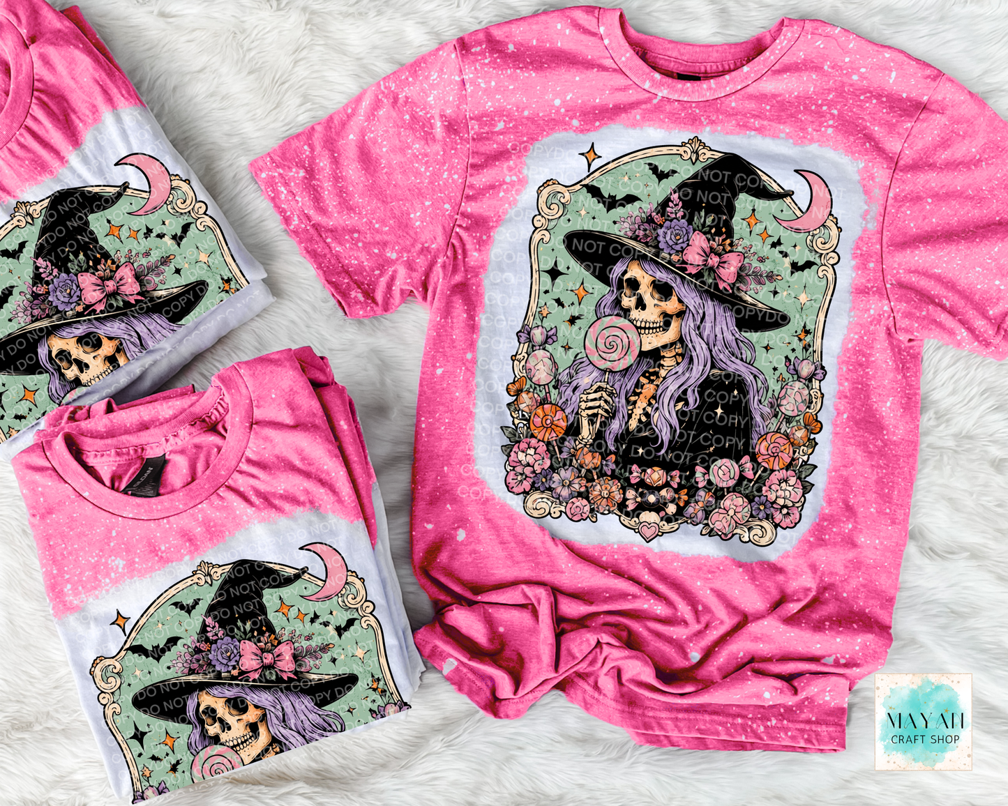 Pink t-shirt with a skeleton wearing a witch hat and flowers design, displayed on a textured surface.