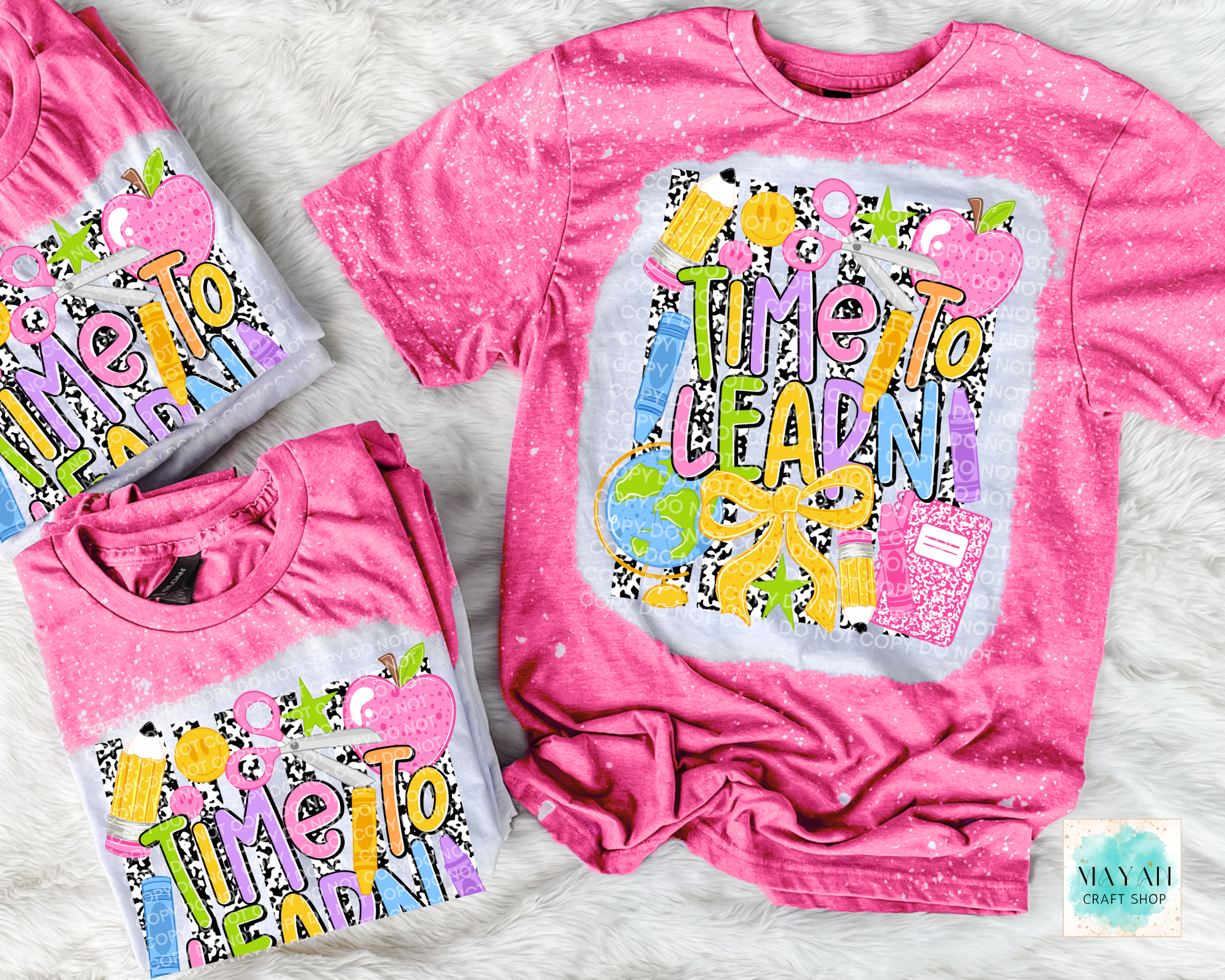 Three pink short-sleeve graphic T-shirts arranged on a white faux-fur surface. The shirts feature a colorful retro-style 'Time To Learn' design with apples, pencils, and a notebook.