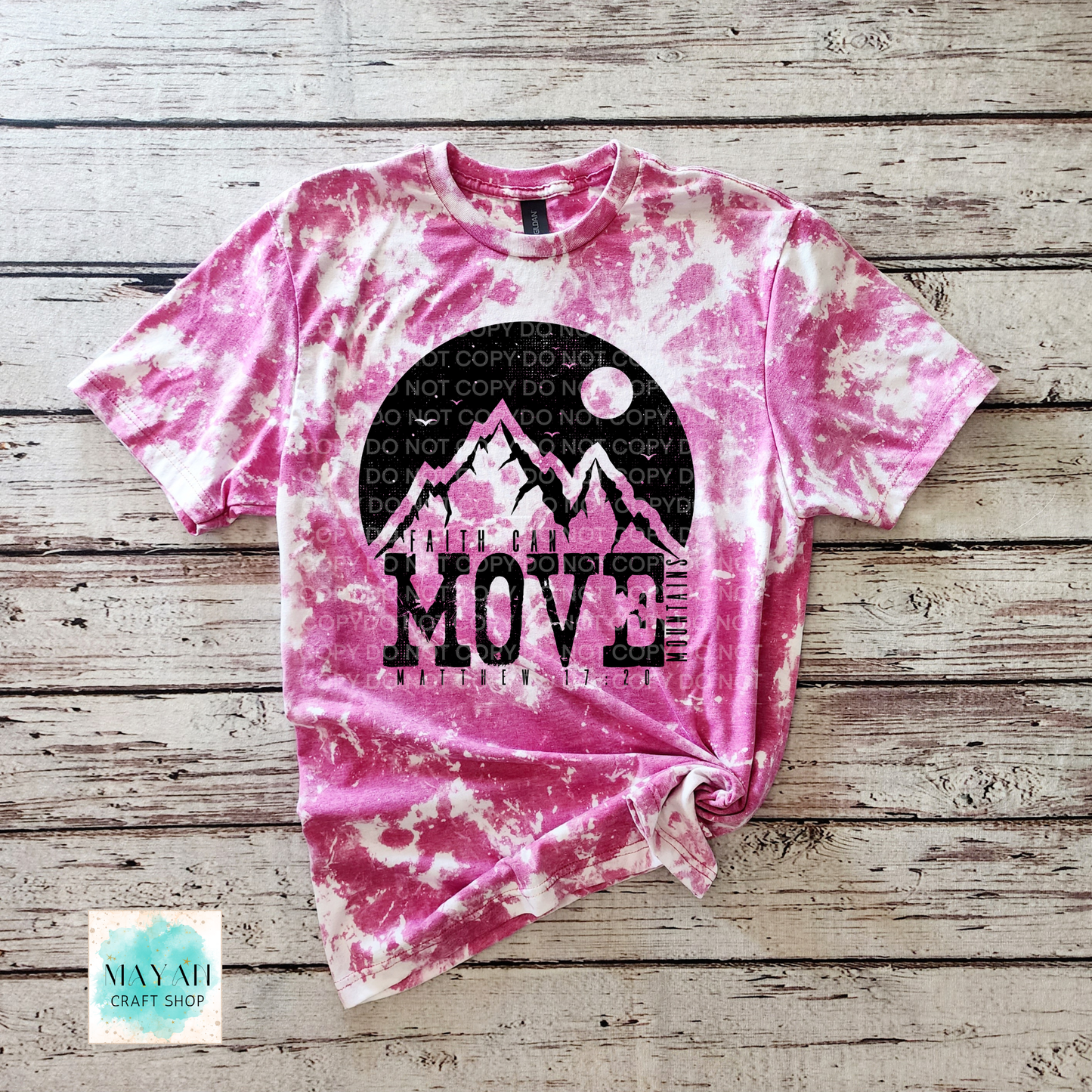 Pink tie-dye t-shirt with mountain design and 'Move Mountains' text on a wooden surface.