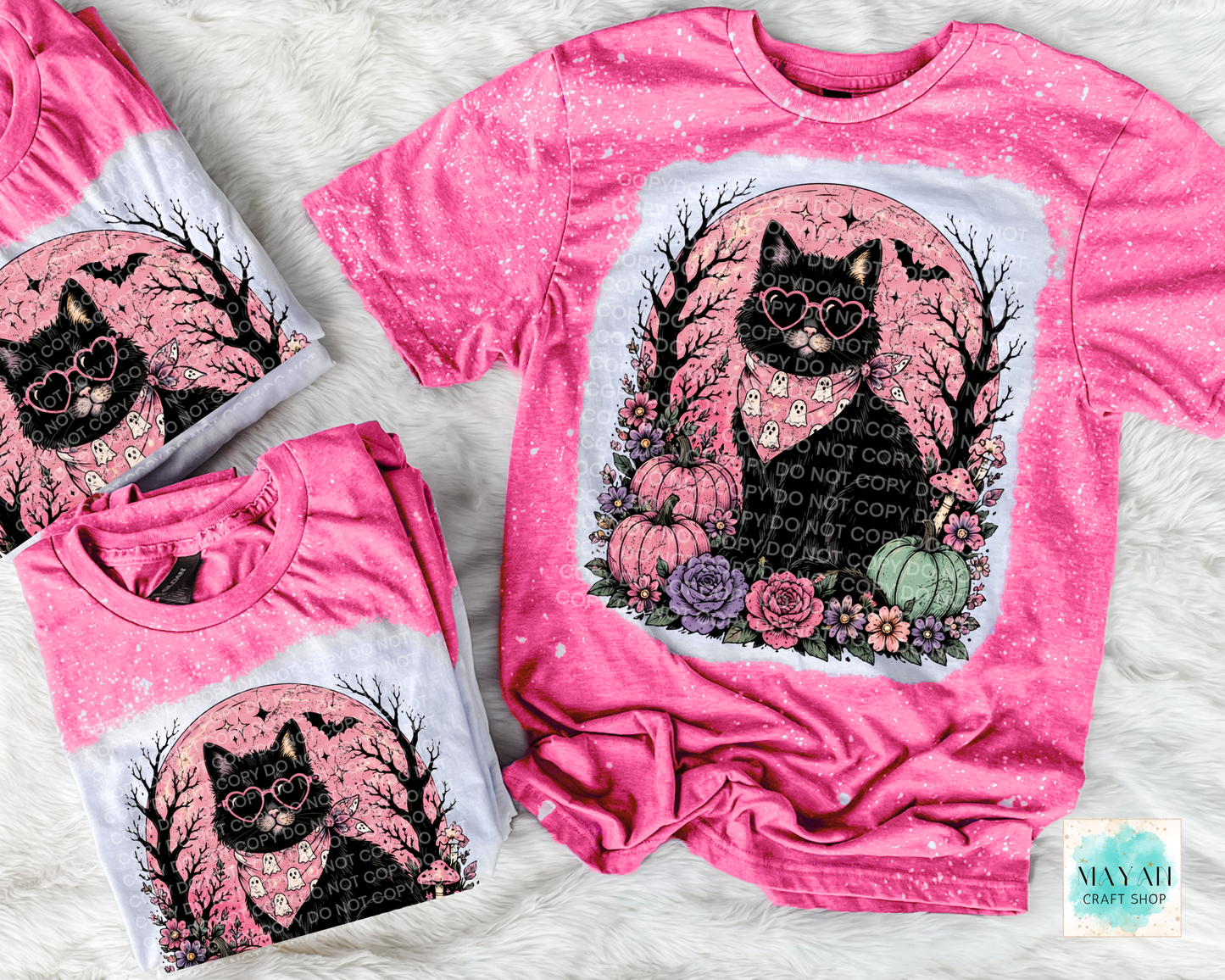 Pink t-shirt with black cat design on a textured surface