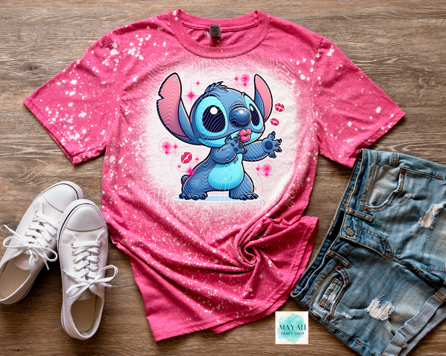 Pink t-shirt with cartoon character, white sneakers, and denim shorts on a wooden surface