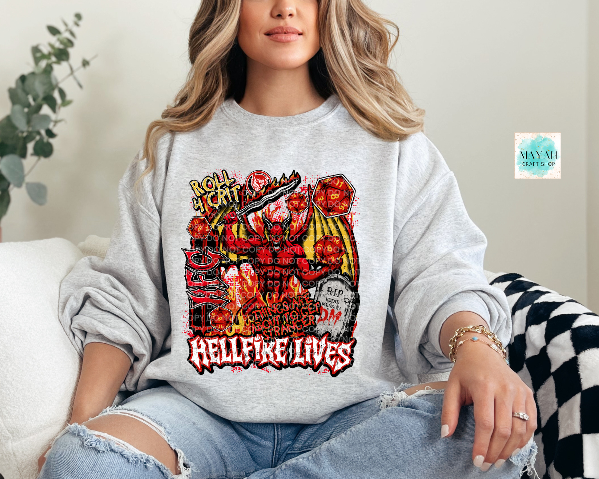 Person wearing a gray sweatshirt with a graphic design and text, sitting on a couch.