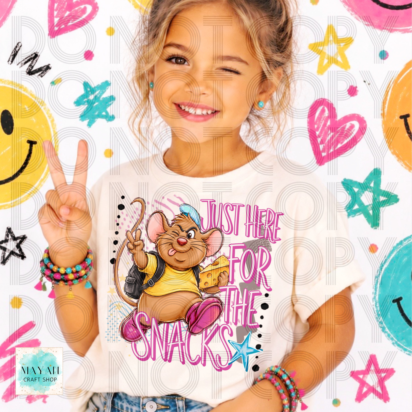 A young girl with blonde hair is winking and making a peace sign while wearing a white graphic t-shirt. The shirt features a cartoon mouse character wearing a yellow shirt and pink sneakers, with the text 'JUST HERE FOR THE SNACKS'.
