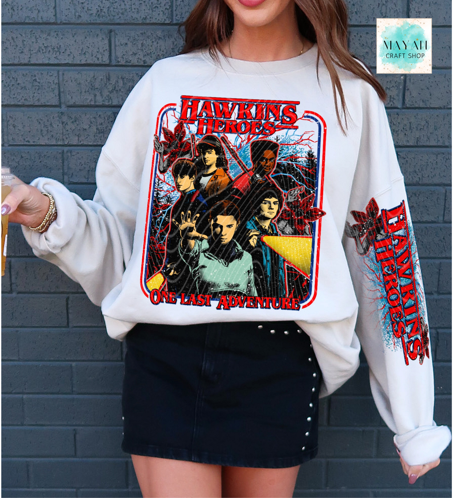 Person wearing a white sweatshirt with  'Heroes' graphic design against a gray brick wall.