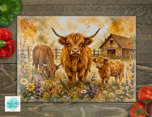Cutting board of three Highland cows in a field with flowers and a barn on a wooden surface.