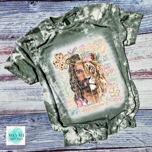 Bleached green t-shirt with a colorful lion graphic on a wooden surface