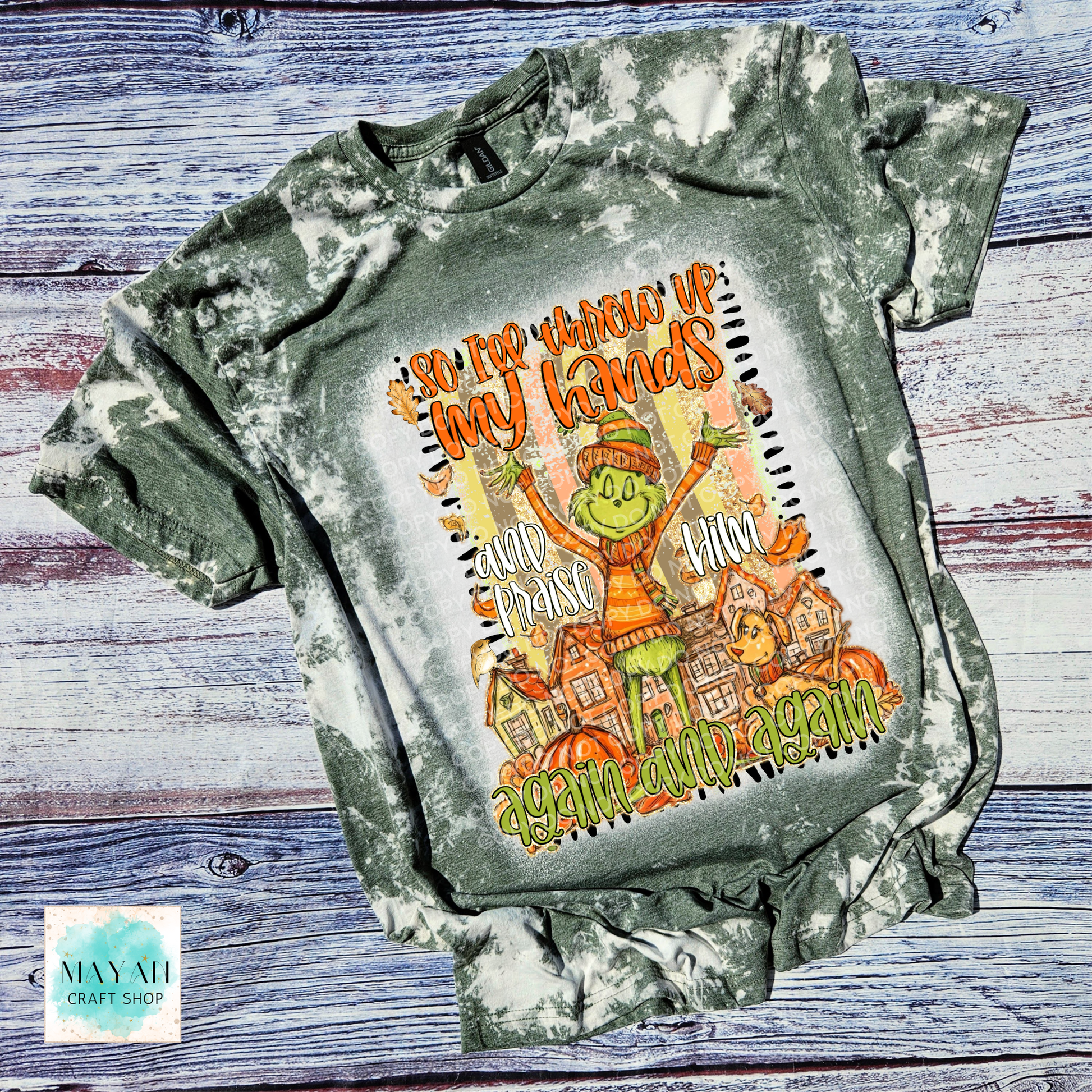 Bleached green t-shirt with a graphic design of a character and text on a wooden surface.