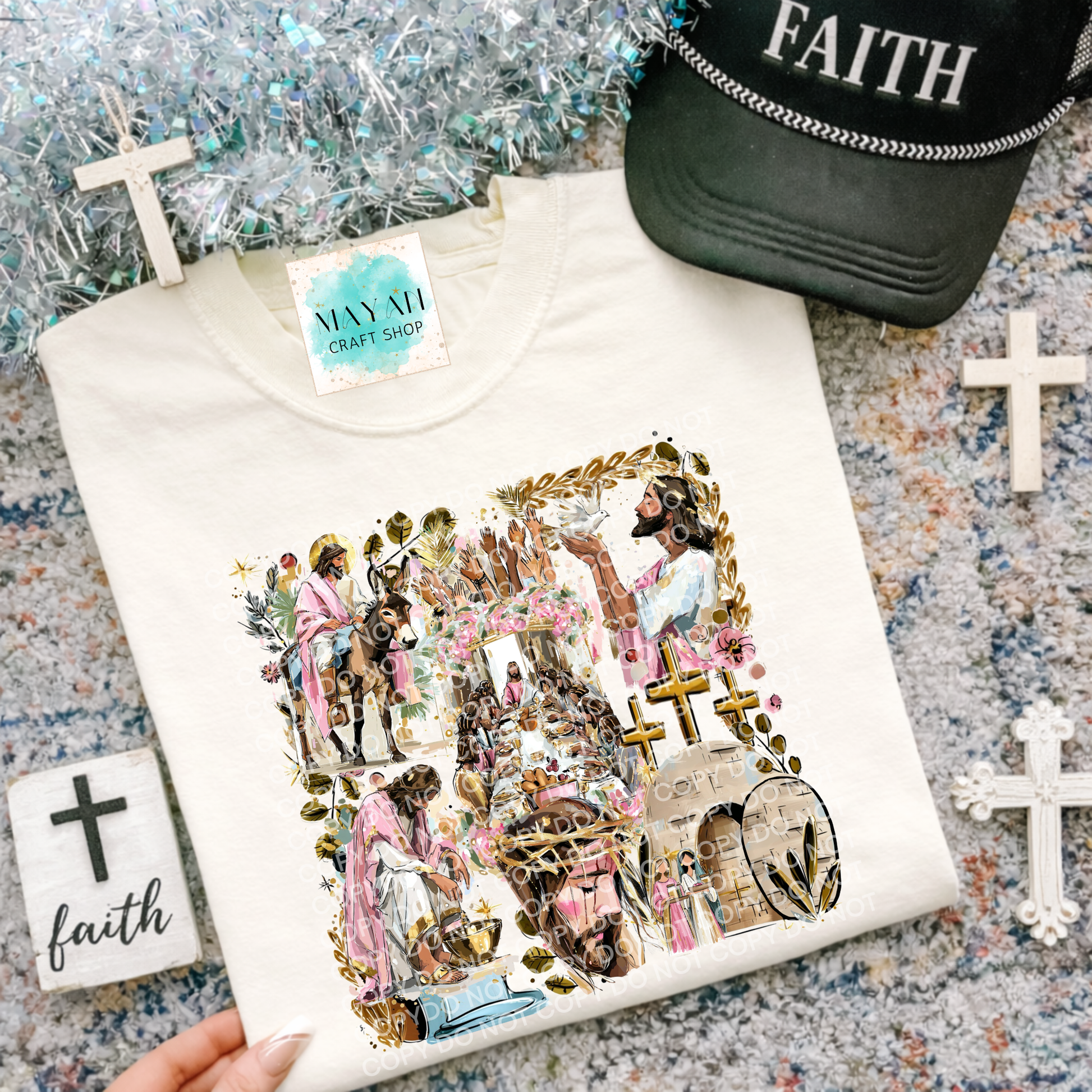White sweatshirt with artistic design of people and crosses on a textured surface with decorative items.