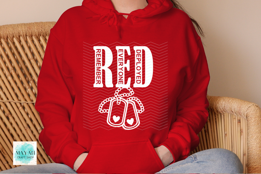 Red hoodie with white text and design, worn by a person sitting on a wicker chair.
