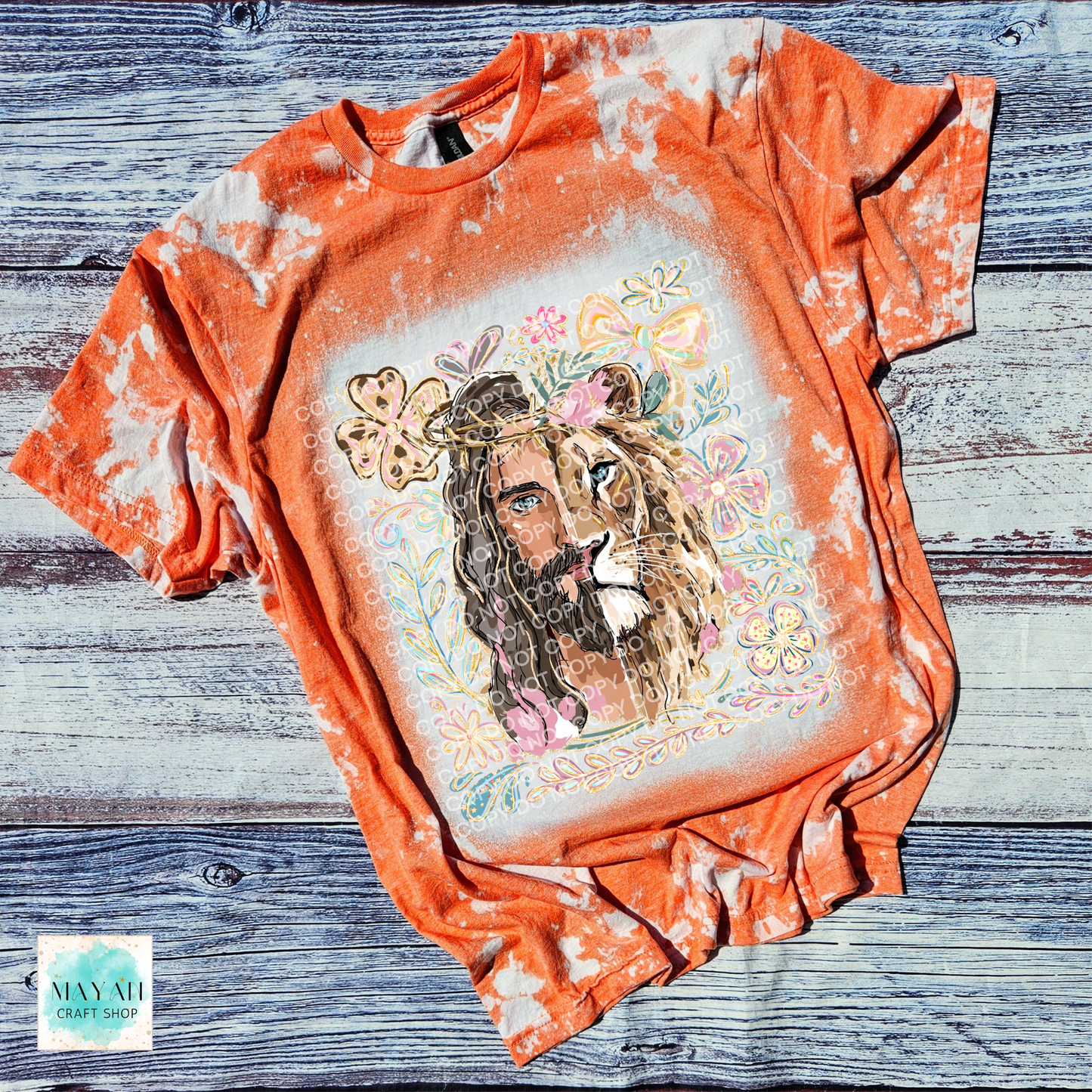 Orange tie-dye t-shirt with a graphic of a lion and flowers on a wooden surface