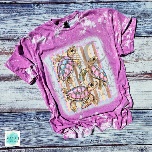Heather orchid t-shirt with turtle design on a wooden surface