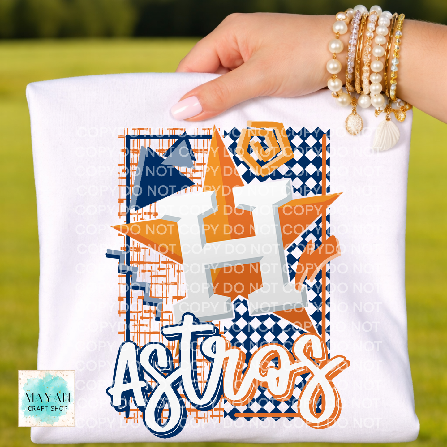 Hand holding a white pillow with decorative text and patterns on a grassy background