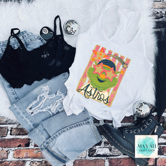White tank top with vibrant graphic, black bralette, denim shorts, and black high-heeled shoes on a brick surface.