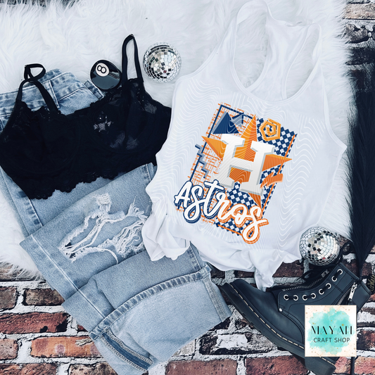 White tank top with vibrant design, black bralette, blue jeans, and black shoes on a brick surface.
