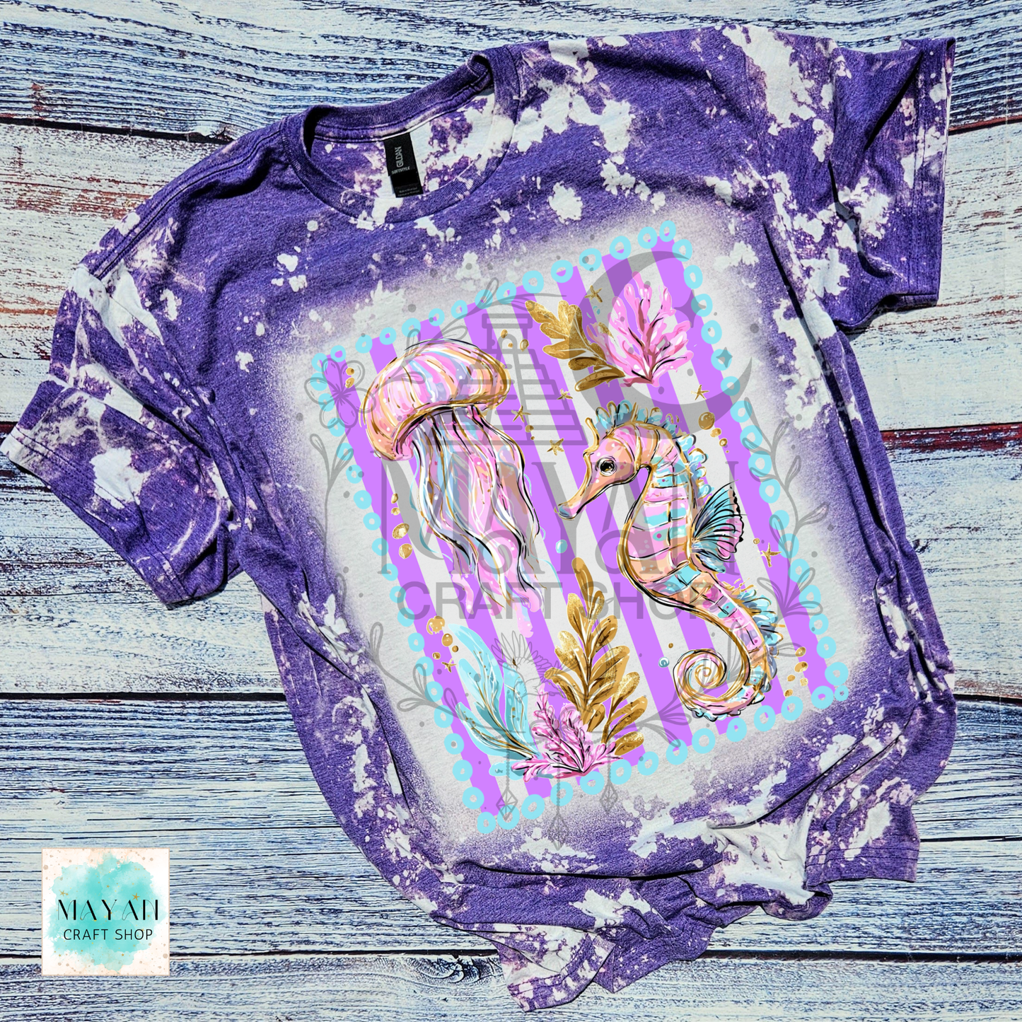 Purple tie-dye t-shirt with a colorful seahorse and jellyfish design on a wooden surface.
