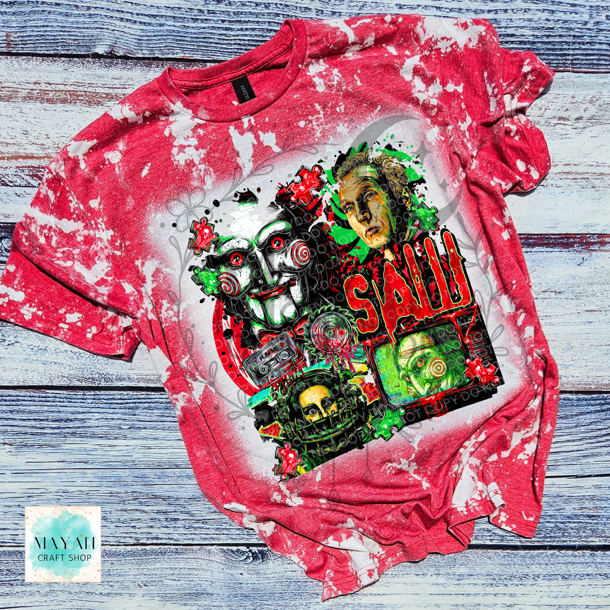 A red bleached graphic t-shirt featuring a horror collage of horror character and skulls. The shirt is laid flat on a rustic, weathered blue-gray wooden plank background.