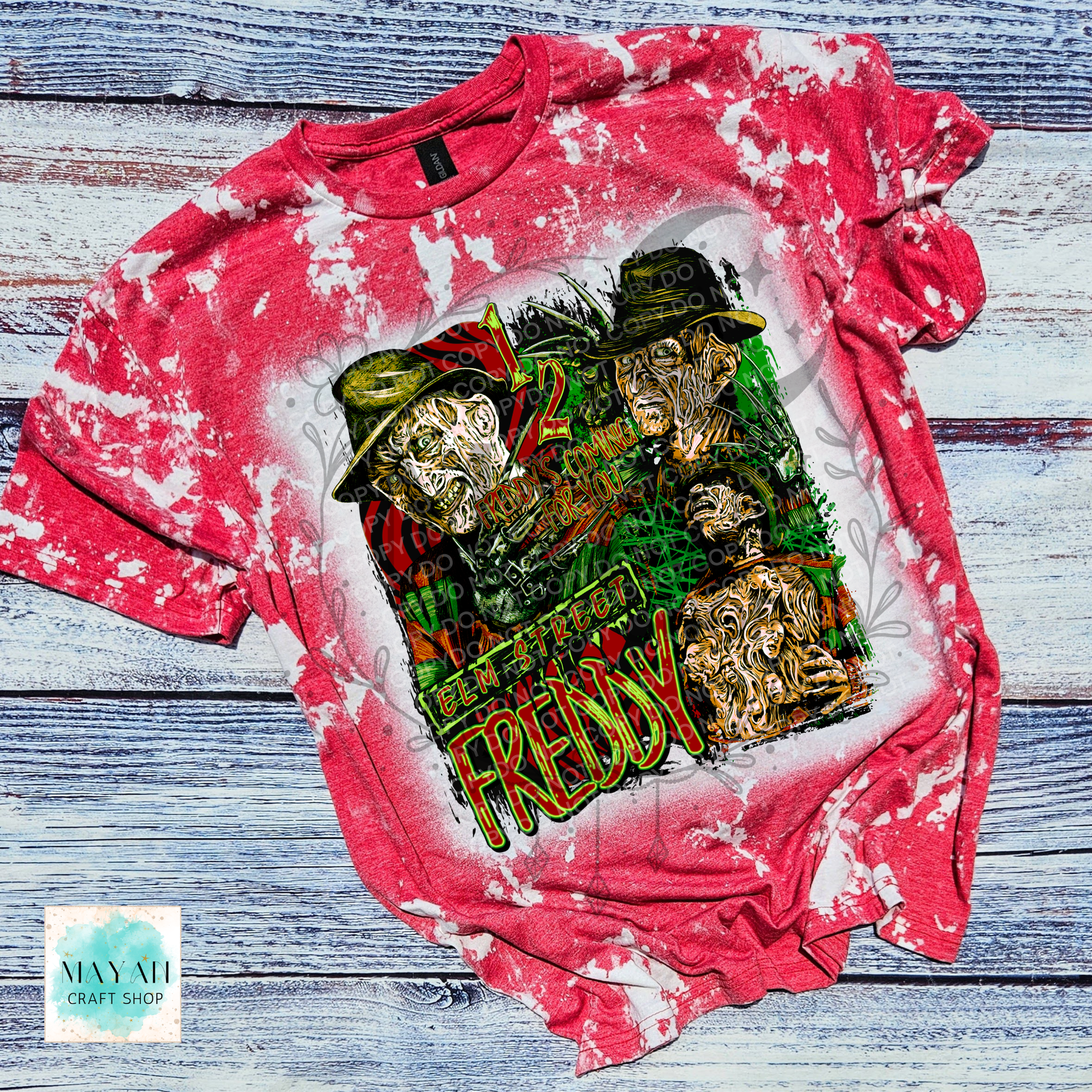 A red bleached graphic t-shirt featuring a horror-themed collage of a horror character with a text. The shirt is laid flat on a rustic, weathered blue-gray wooden plank background.
