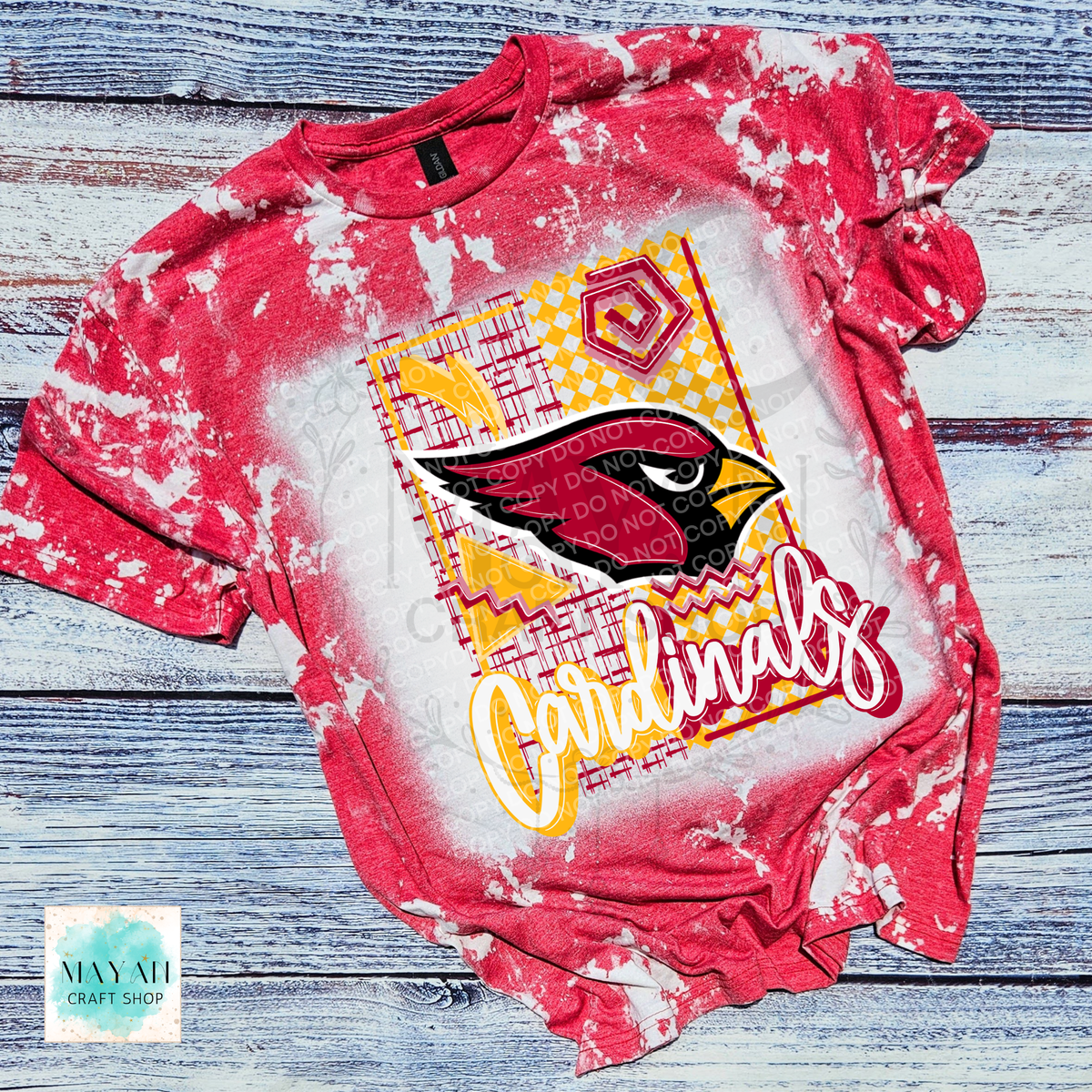 A heather red bleached graphic t-shirt featuring a football team logo on the front, laid flat on a rustic blue-gray wood plank background.