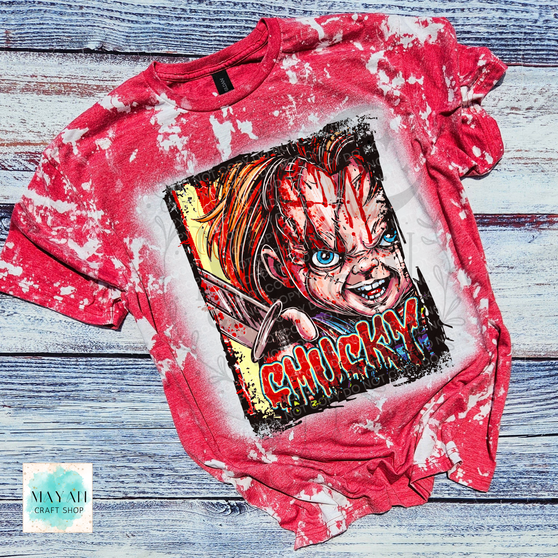 A red bleached graphic t-shirt featuring a horror character print with a text on the front, laid flat on a rustic blue-gray wooden background.