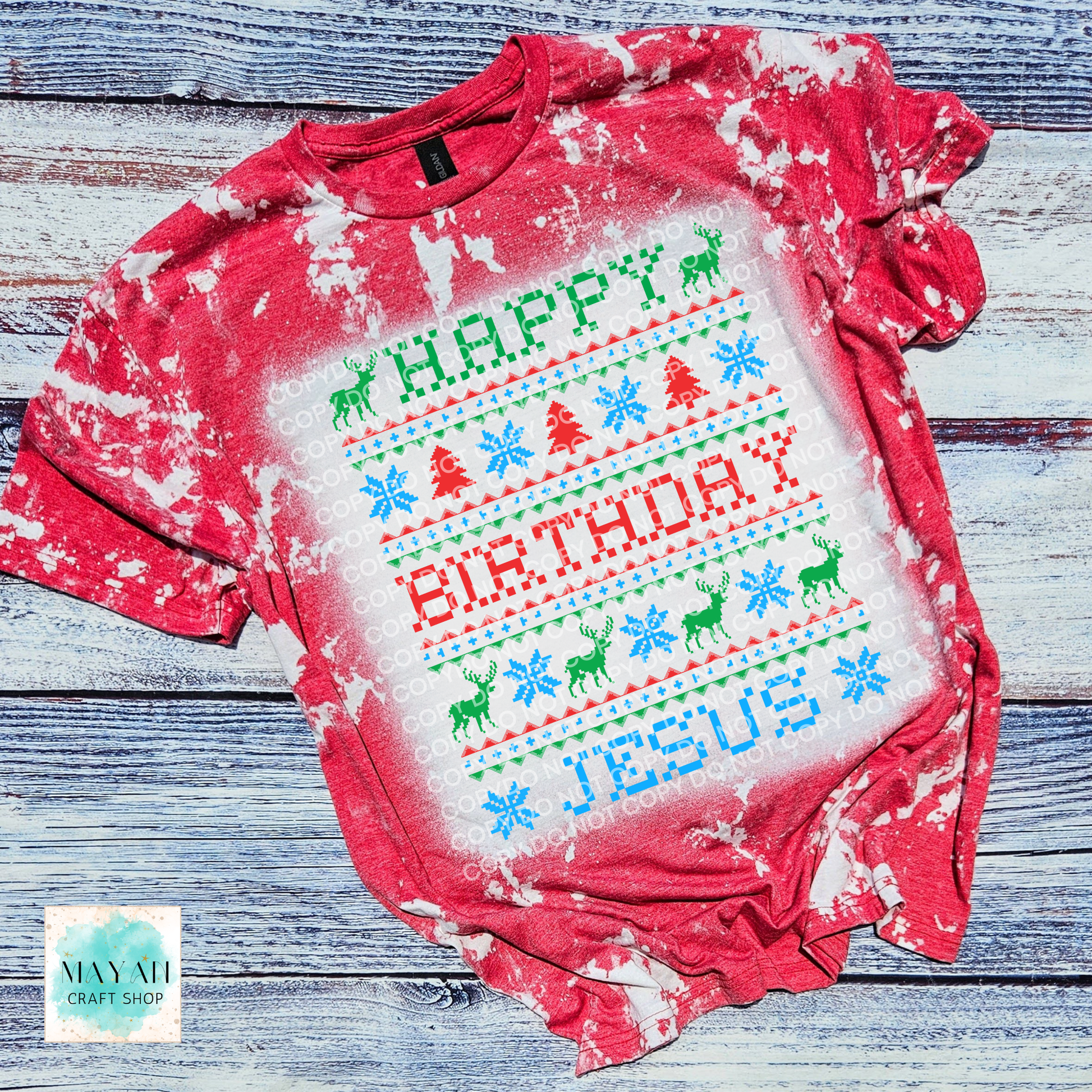 Red shirt with 'Happy Birthday Jesus' text on a wooden surface, featuring a brand logo in the corner.