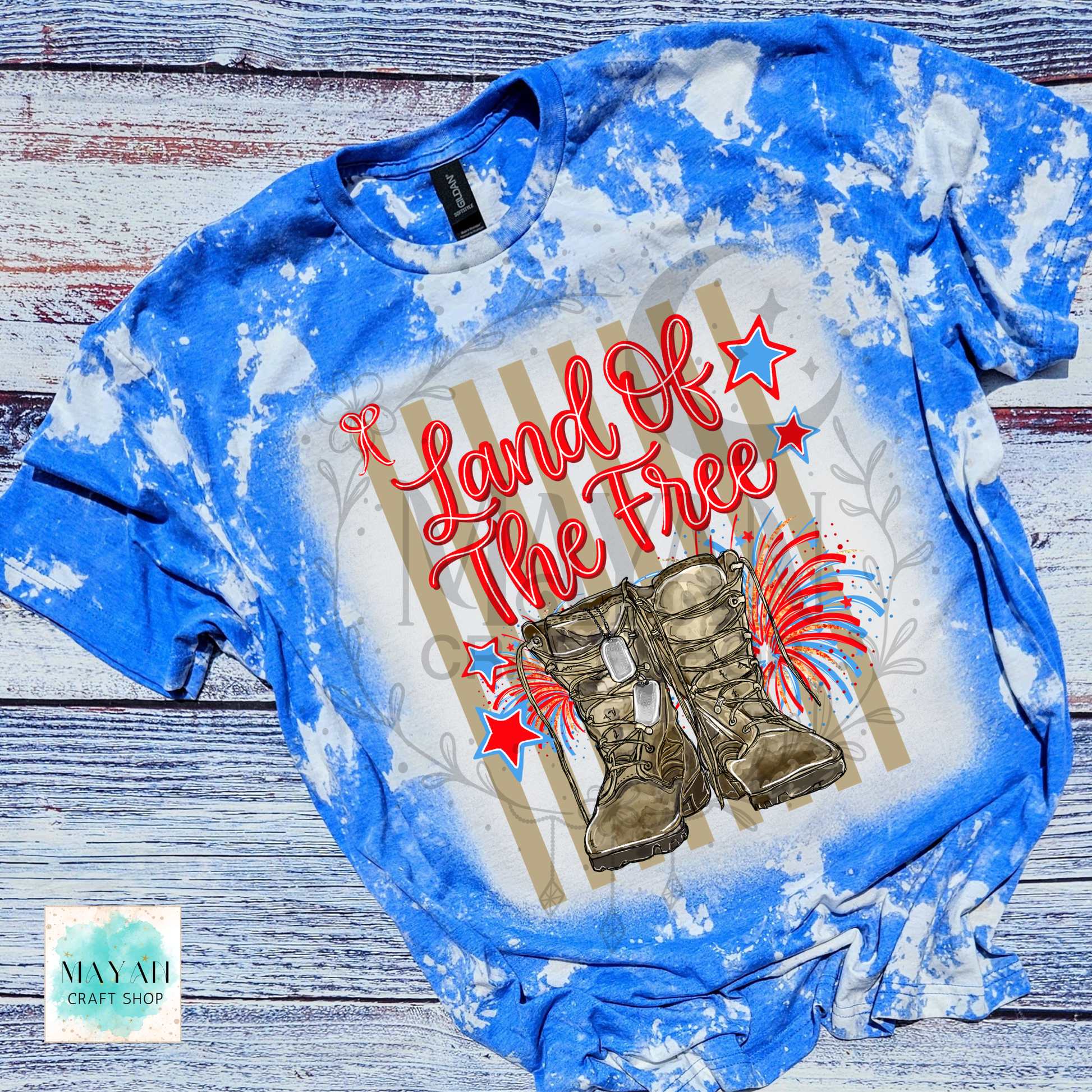 Blue tie-dye t-shirt with 'Land of the Free' text and boots design on a wooden surface.