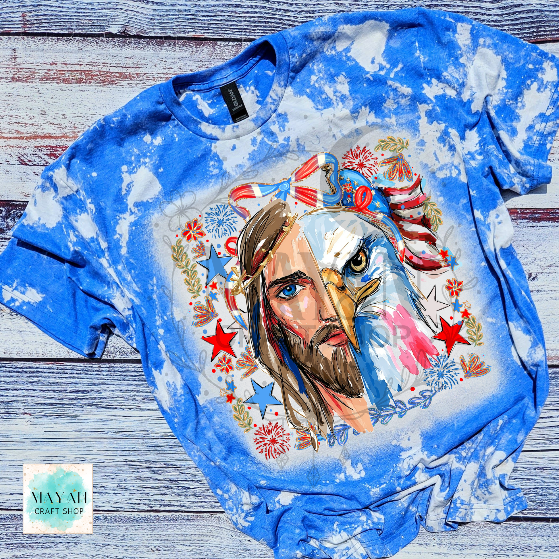 Blue tie-dye t-shirt with a graphic design of a man with an eagle head and American flag elements on a wooden surface.