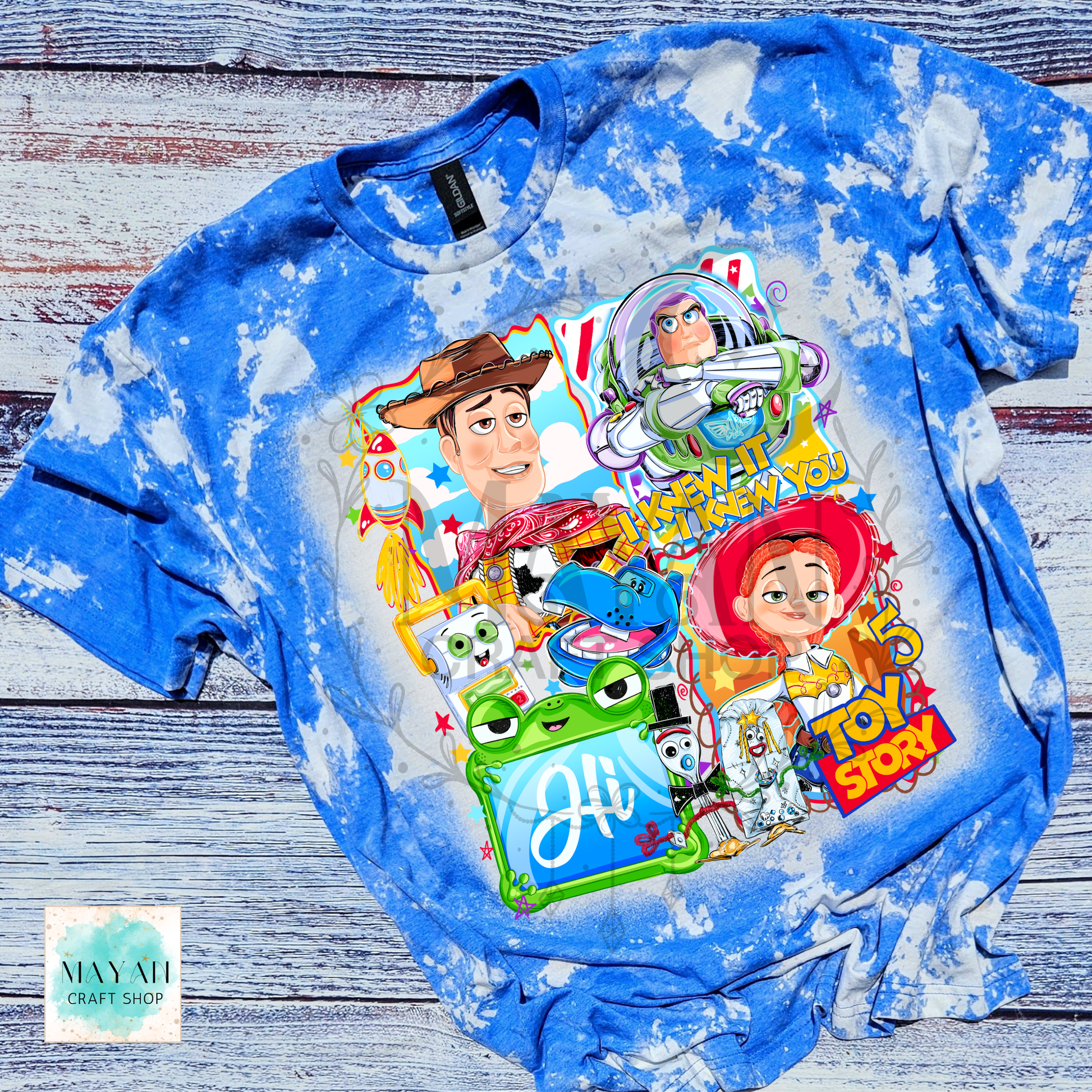 Blue tie-dye long-sleeve shirt with  character graphics on a wooden surface.