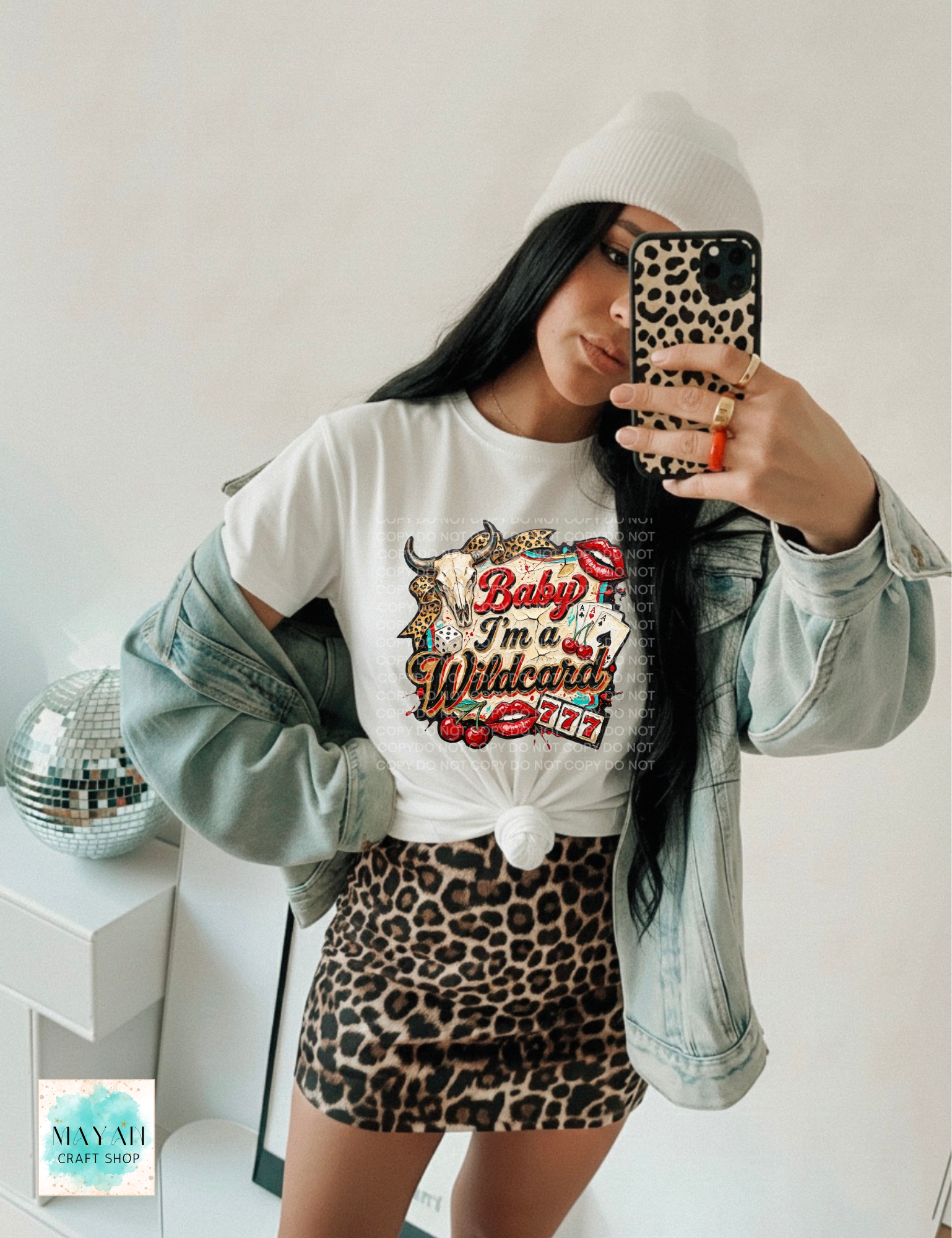 Person wearing a white sweatshirt with graphic design, leopard print skirt, and denim jacket taking a mirror selfie.