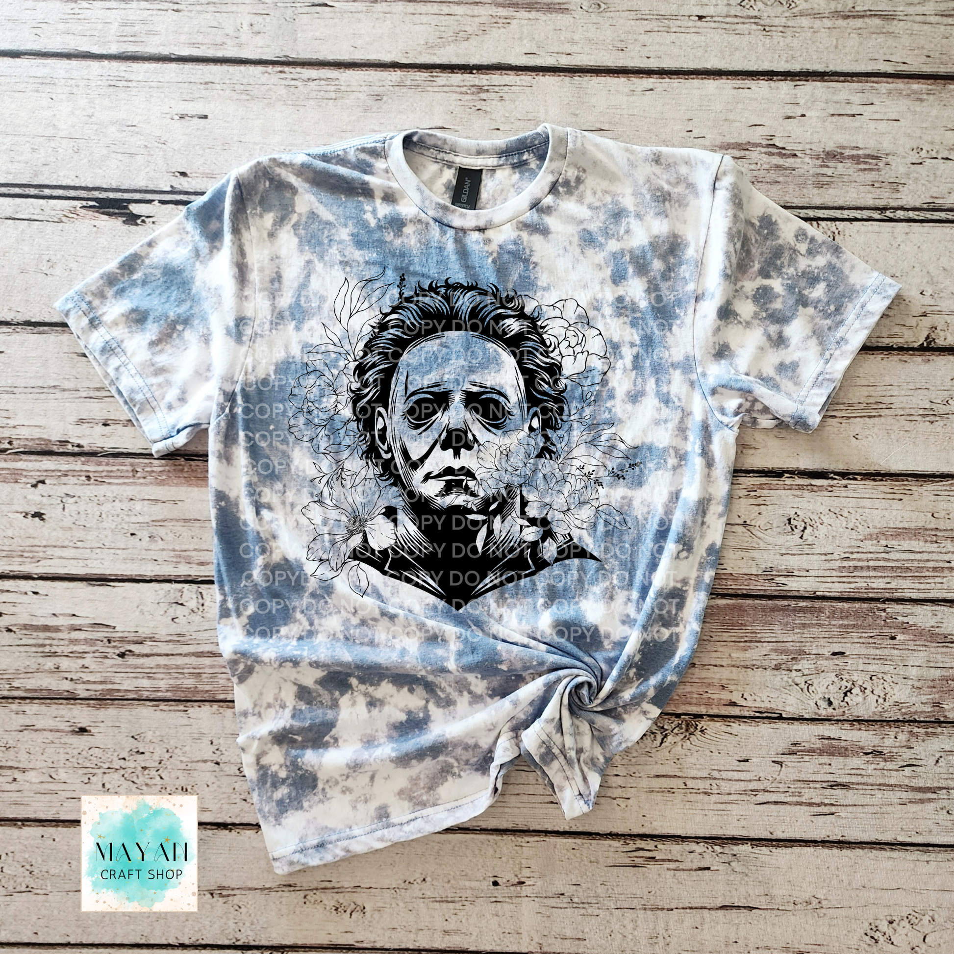 Indigo blue bleached t-shirt with a graphic design on a wooden surface.