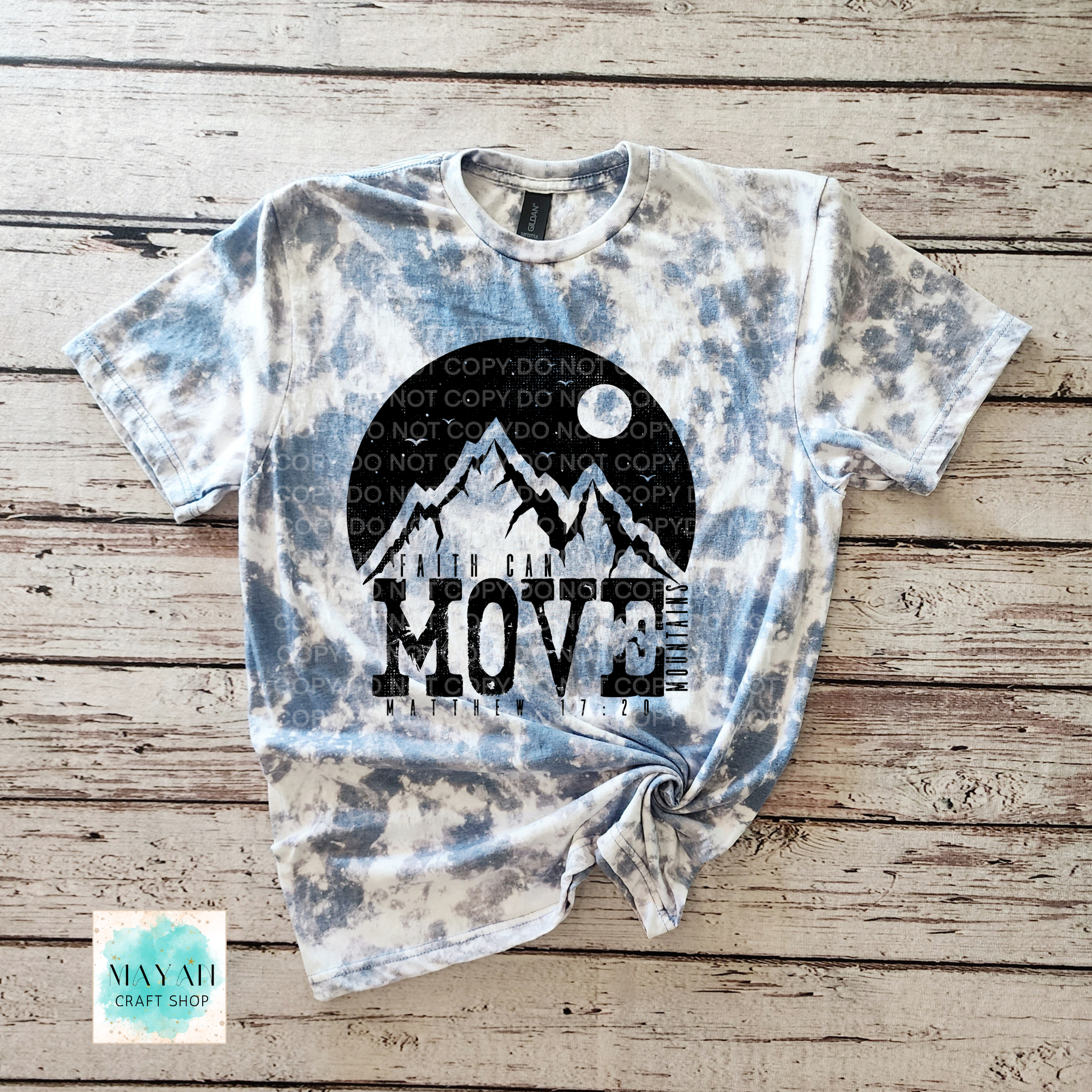 Tie-dye t-shirt with mountain and moon design on a wooden surface, featuring the text 'Do not copy do not move'.