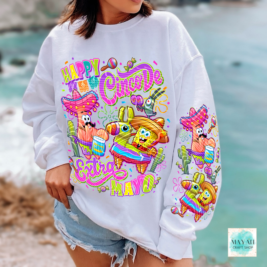 Person wearing a white sweatshirt with colorful 'Happy Cinco De Mayo' design at the beach.