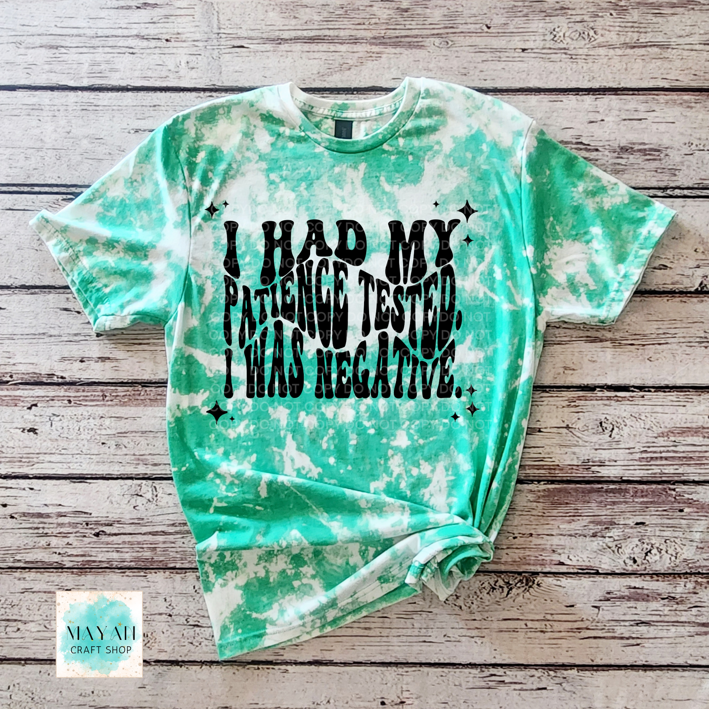 Green tie-dye t-shirt with text on a wooden surface, brand 'Mayan Craft Shop'.