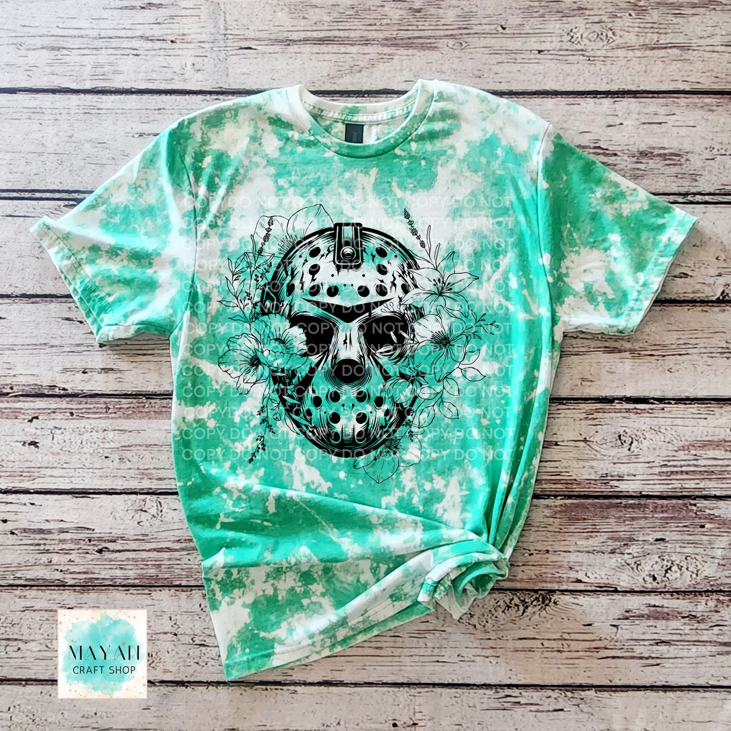 Green tie-dye t-shirt with a black graphic design on a wooden surface