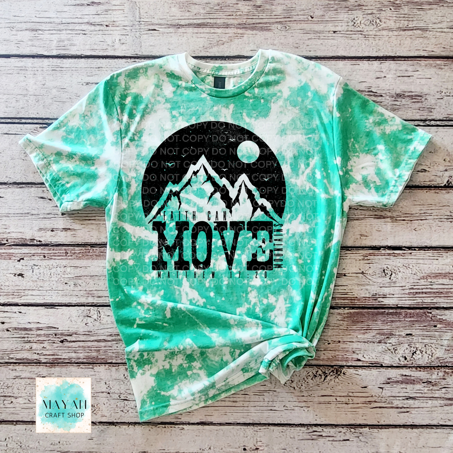 Green tie-dye t-shirt with mountain graphic and 'MOVE' text on a wooden surface