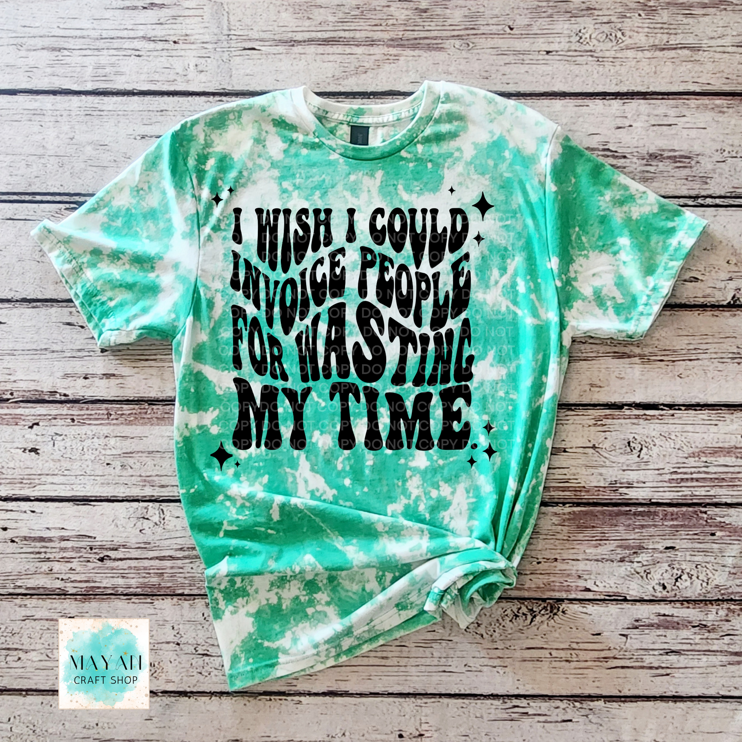Green tie-dye t-shirt with black text on a wooden surface, featuring the brand 'Mayan Craft Shop'.