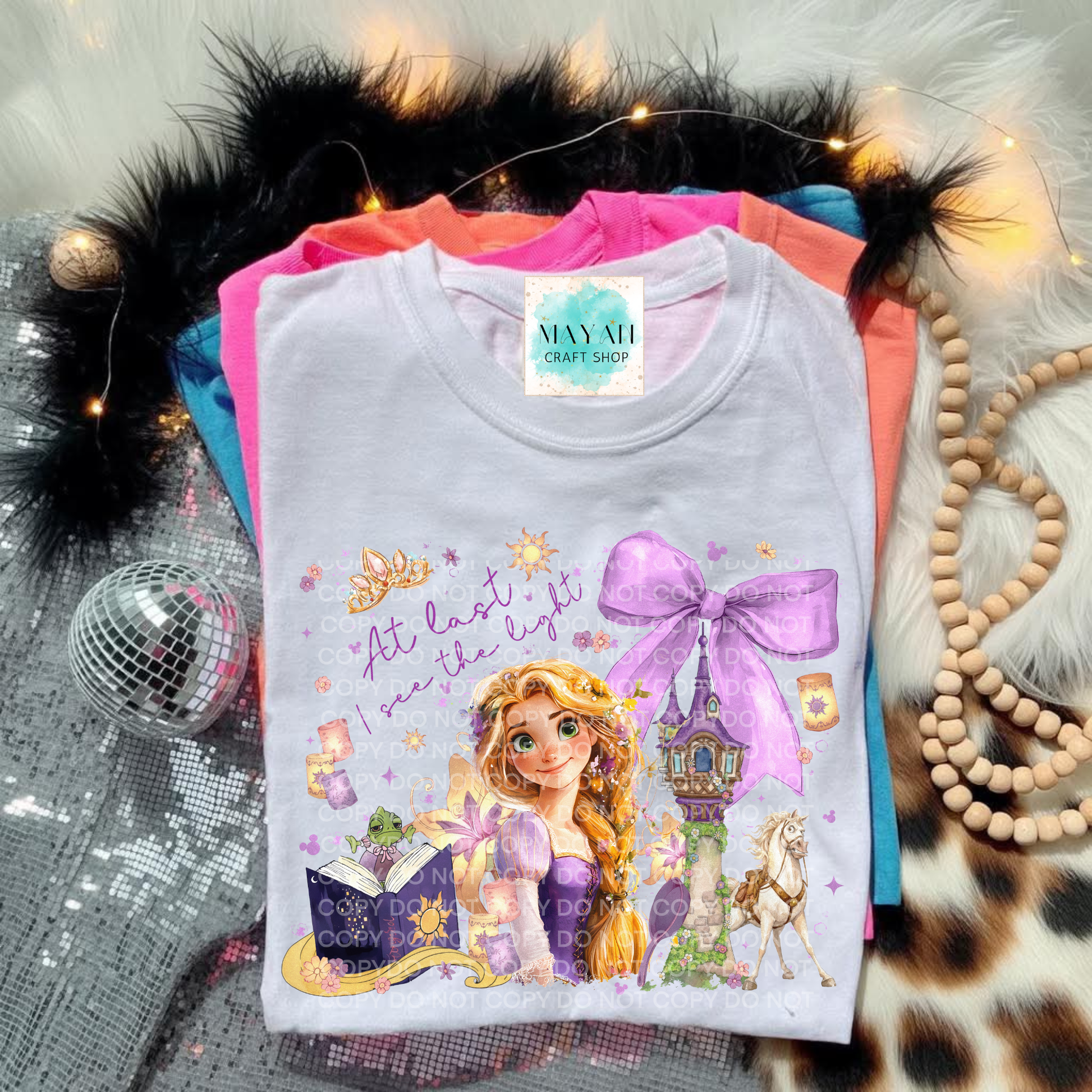 T-shirt with a princess design and text, placed on a textured surface with decorative items.