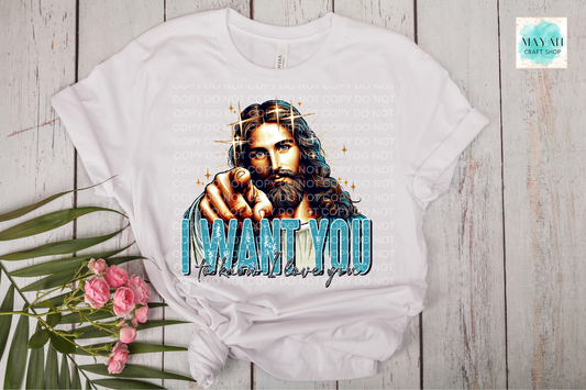 White t-shirt with graphic design of a bearded man and text 'I WANT YOU' on a wooden surface with flowers.
