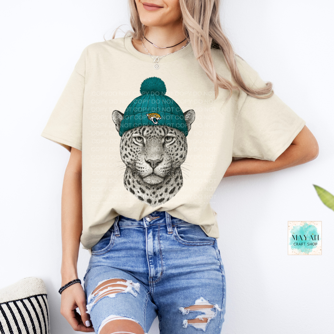 Person wearing a beige t-shirt with a jaguar graphic and blue jeans on a white background