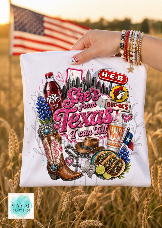 T-shirt with Texas-themed graphics and text held in a field with an American flag in the background.