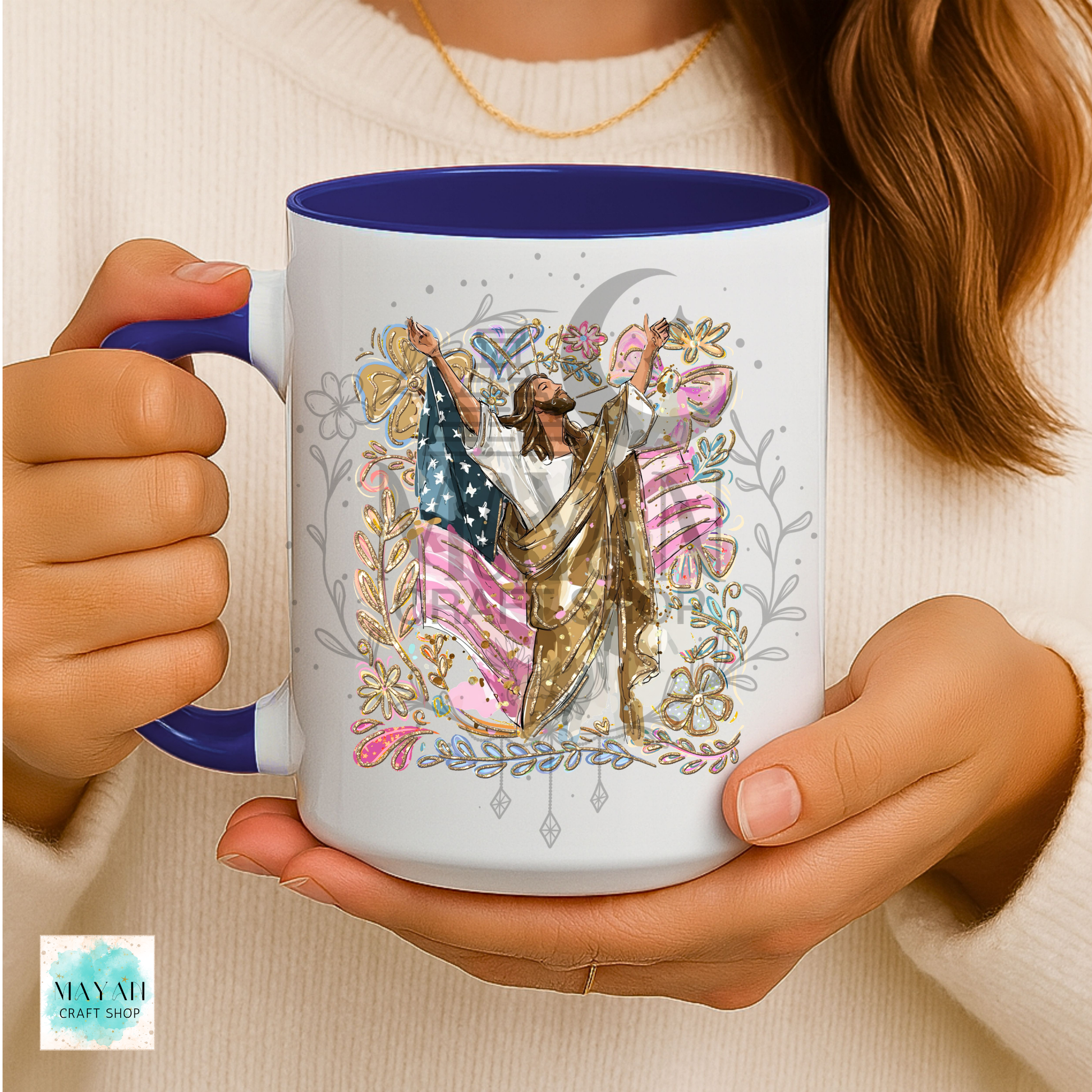 Person holding a mug with a colorful design featuring a flag and angelic figure.
