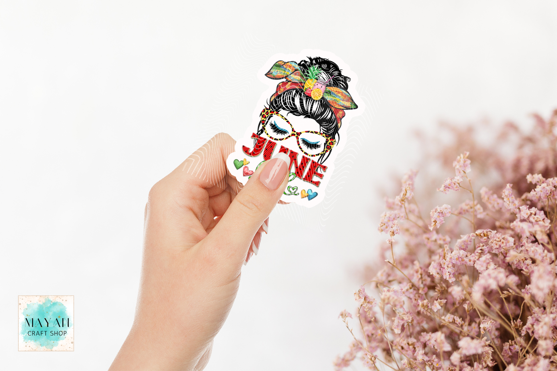 Hand holding a colorful sticker with text and graphics on a white background