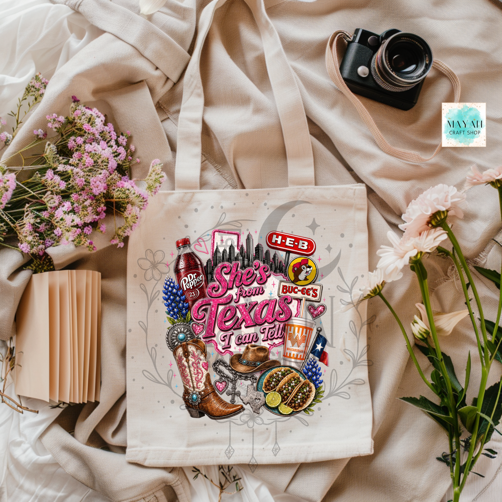 Tote bag with Texas-themed graphics on a light fabric background with flowers and a camera.