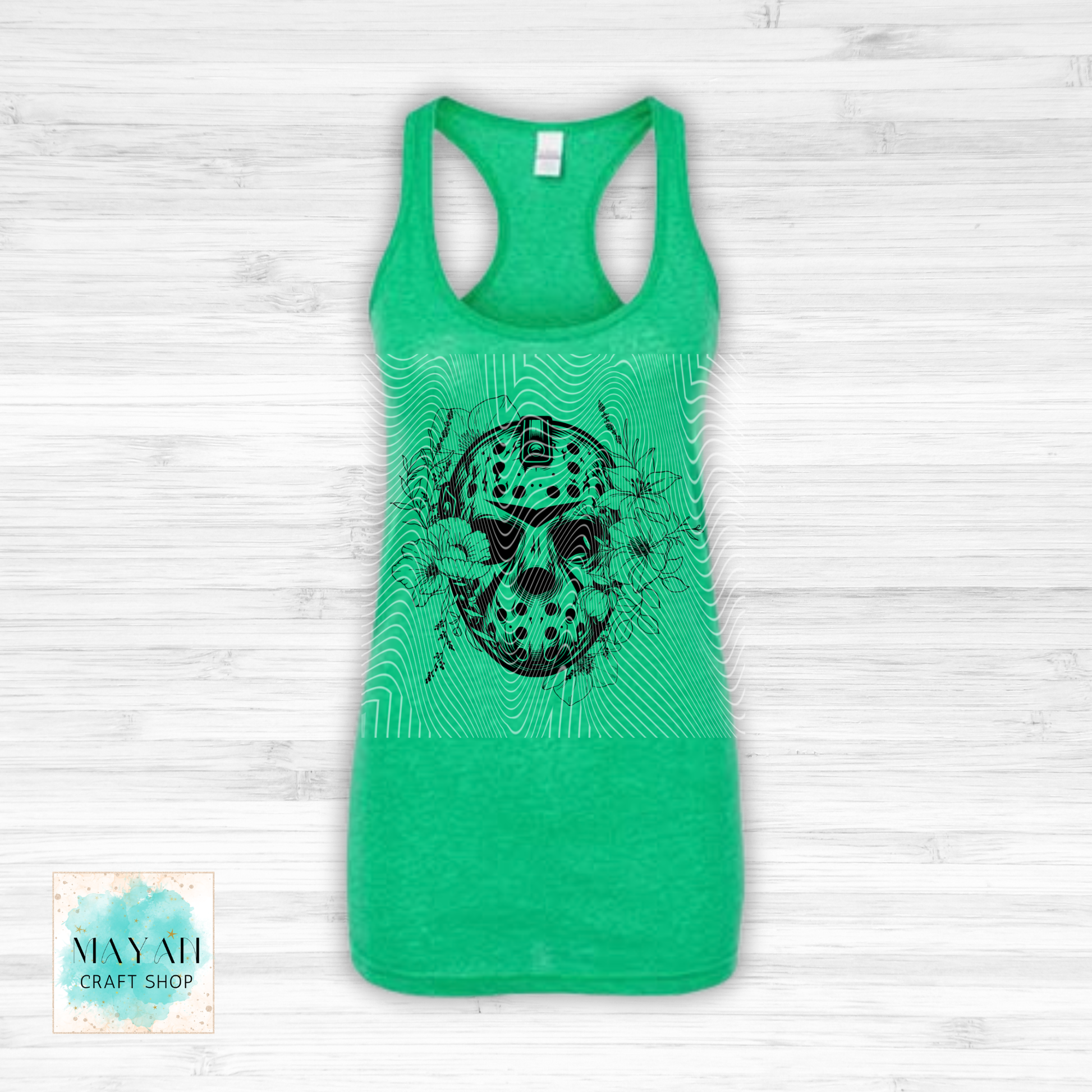 Green tank top with a black graphic design on a light wooden surface.