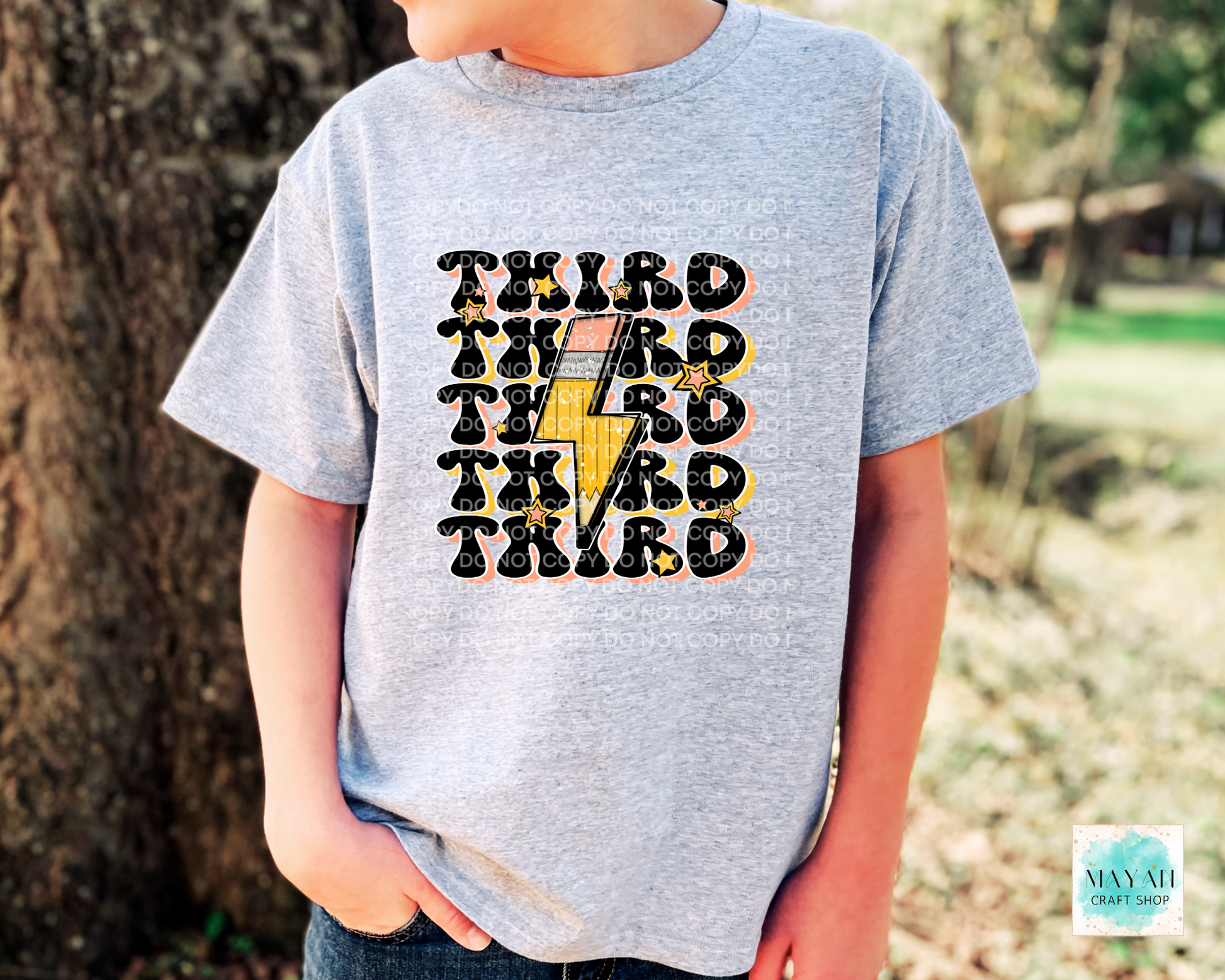 Child wearing a gray t-shirt with 'THIRD' printed multiple times, outdoors.
