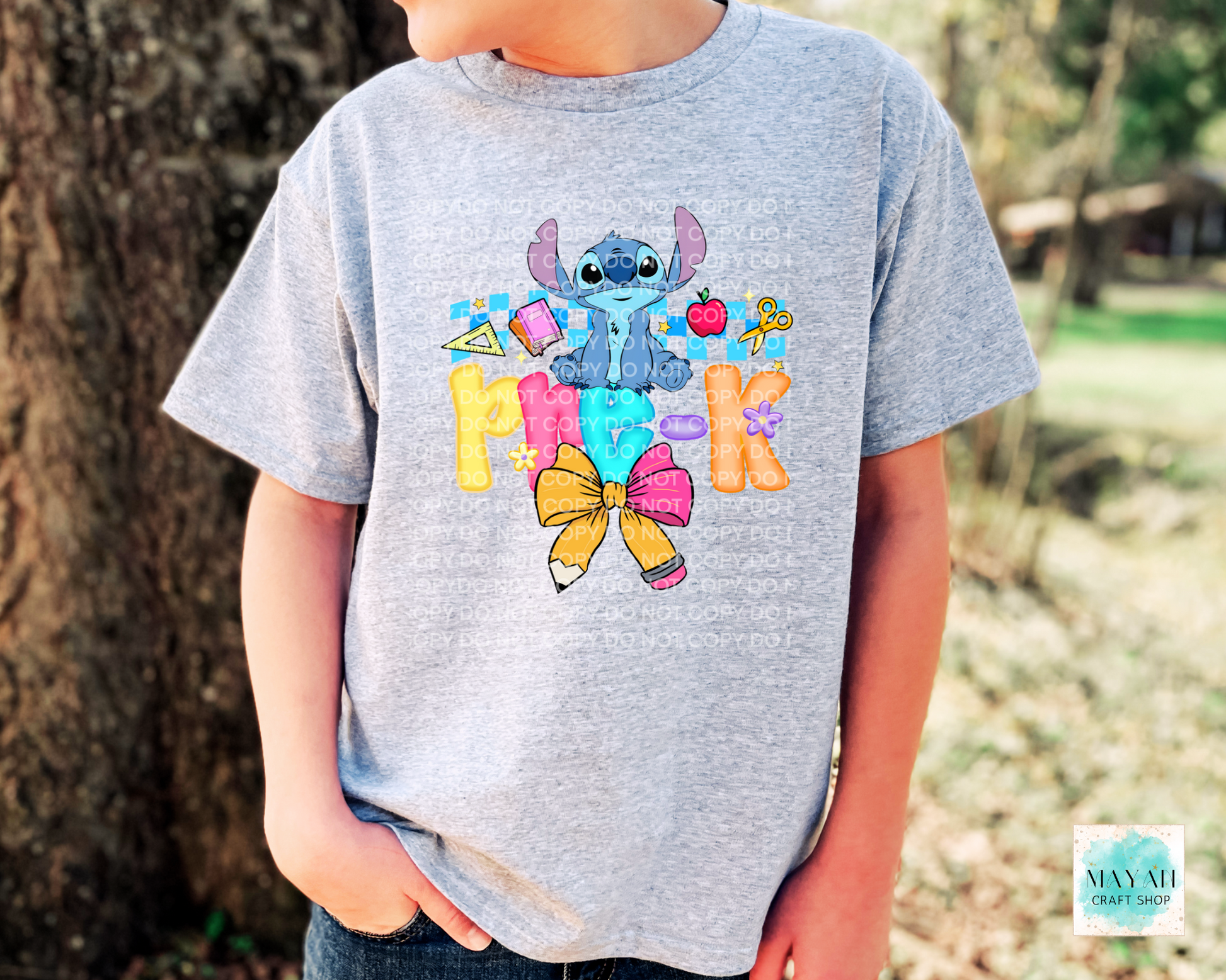 Child wearing a gray t-shirt with colorful character design and text outdoors.