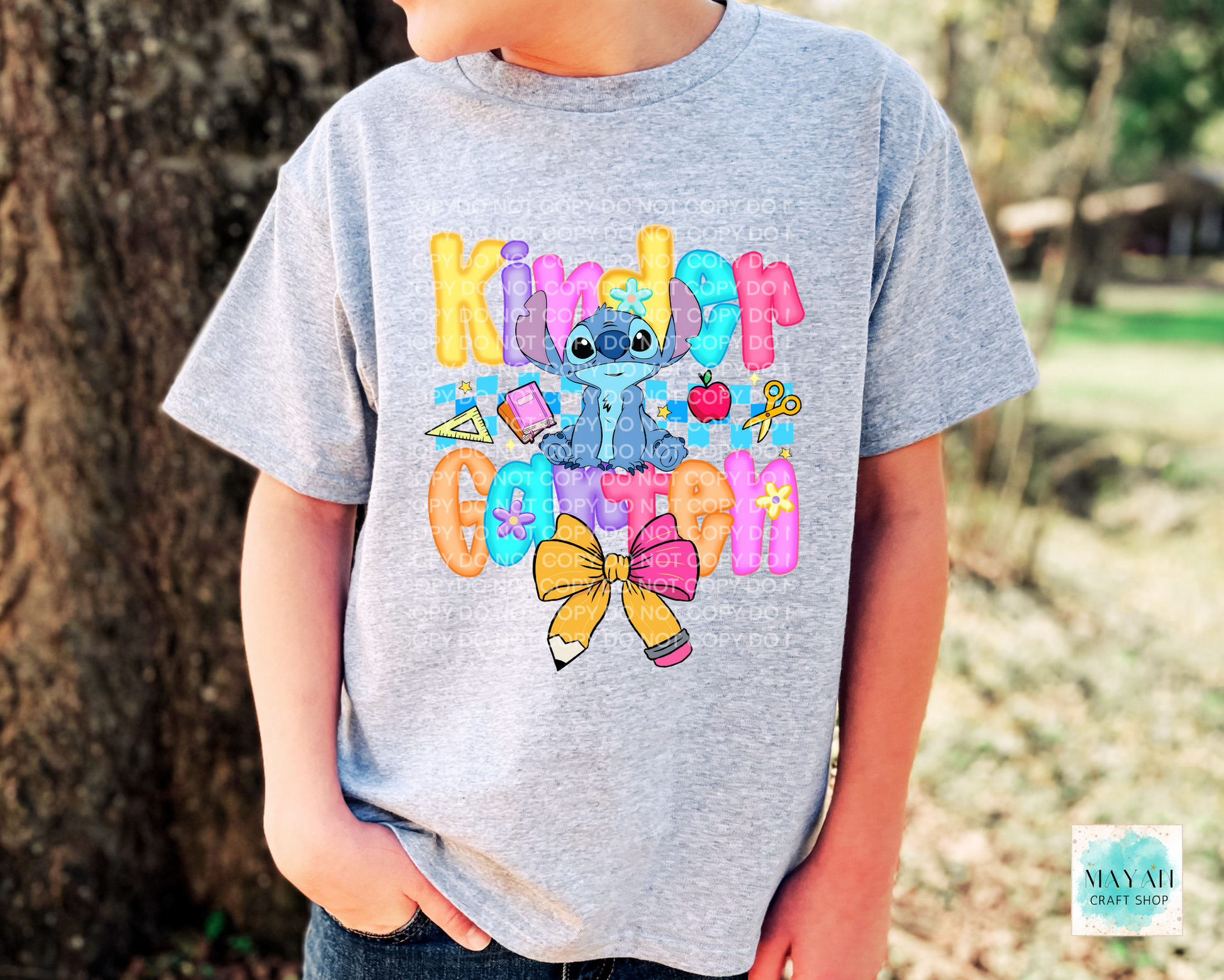 Child wearing an ash gray t-shirt with colorful graphics and text, standing outdoors.