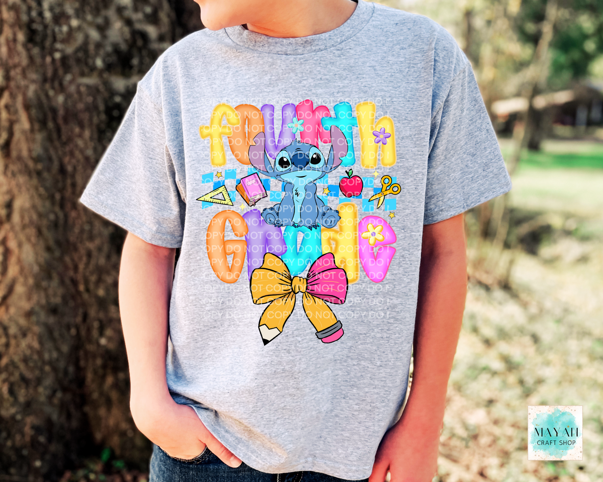 Child wearing a gray t-shirt with a colorful design featuring a character and text, standing outdoors.