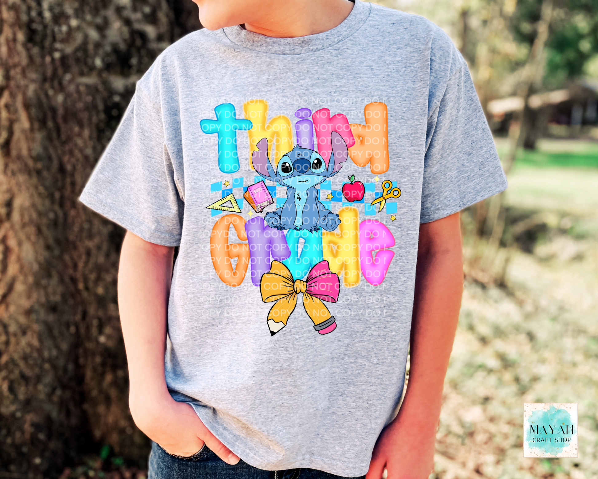 Child wearing a gray t-shirt with colorful text and cartoon character outdoors